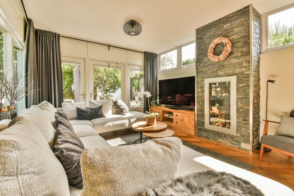 Table with chairs and flowers located near lounge area and kitchen in spacious room of contemporary apartment