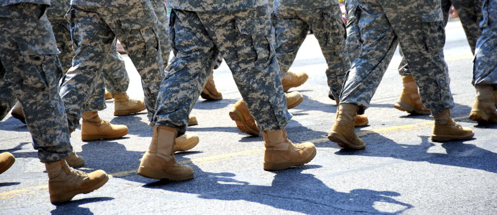 Army military soldiers marching in a parade outdoors.