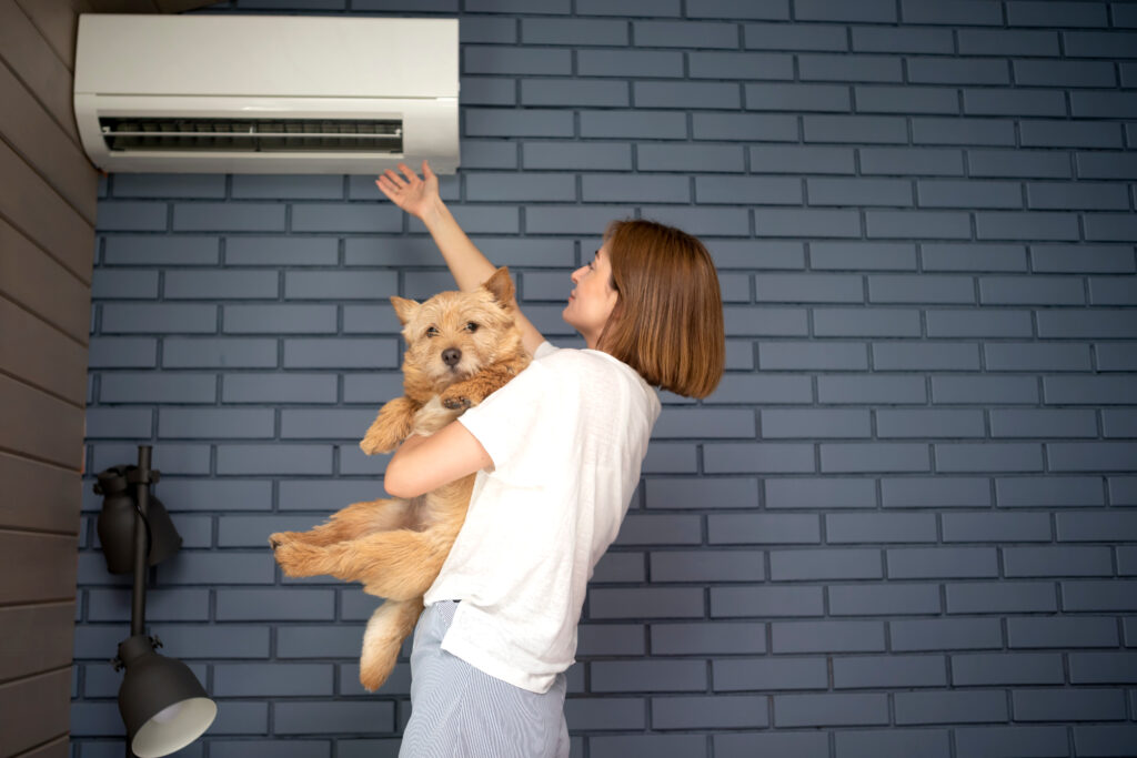 Young woman and her cute dog suffering from extreme heat, record breaking summer heat, trying to keep cool and well air at home