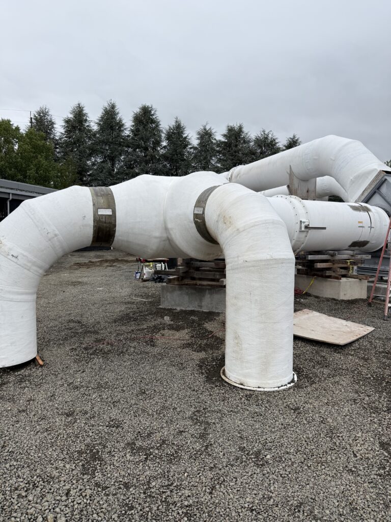 Large white fiberglass exhaust ductwork with flanged elbow joints